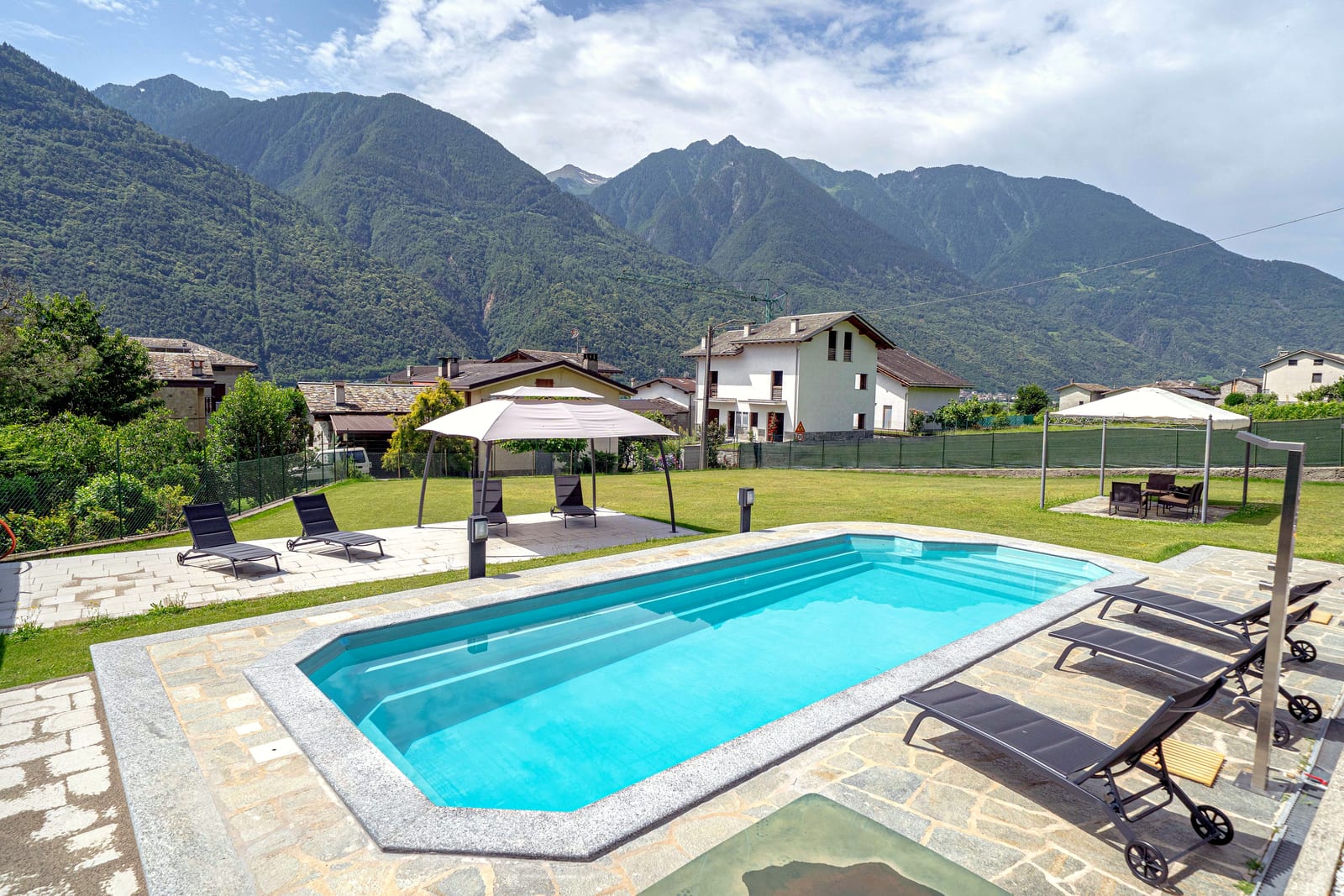 Piscina e giardino con sdraio e ombrelloni, vista sulle Alpi Retiche